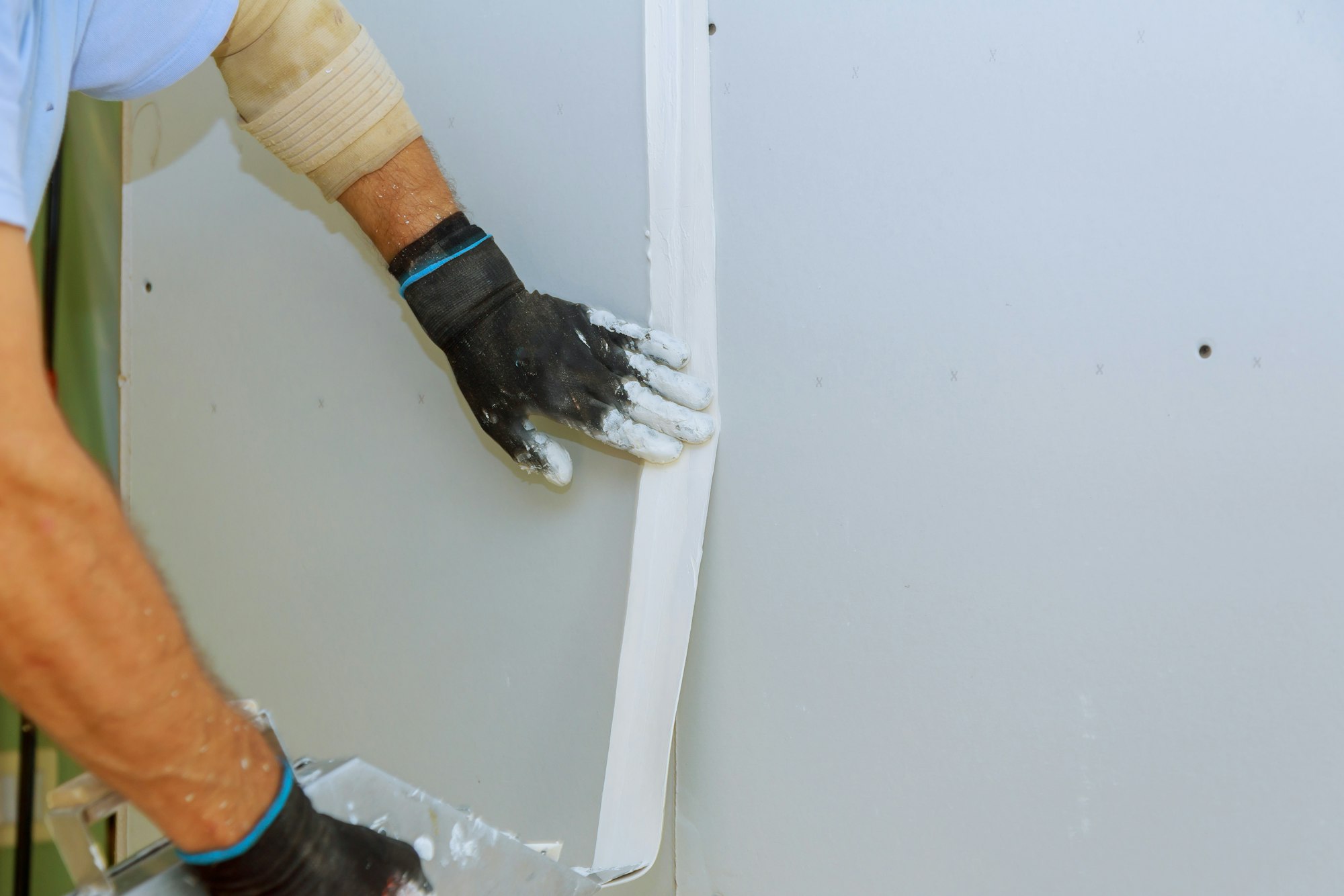 Repair work and construction worker in overalls plastering a wall with finishing putty using a putty